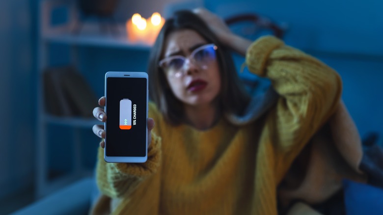 Young woman holding phone with 10% battery