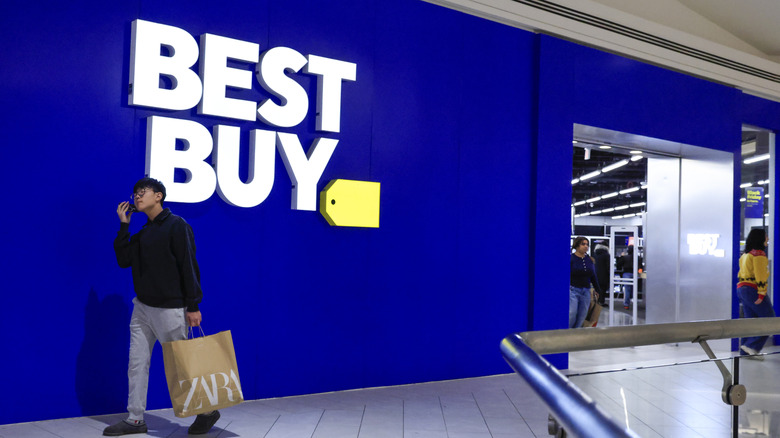 Man walking in front of a Best Buy store during a Black Friday sale event