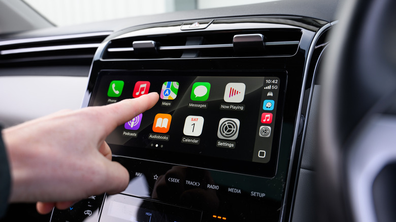 Person using Apple CarPlay features on their car's infotainment screen
