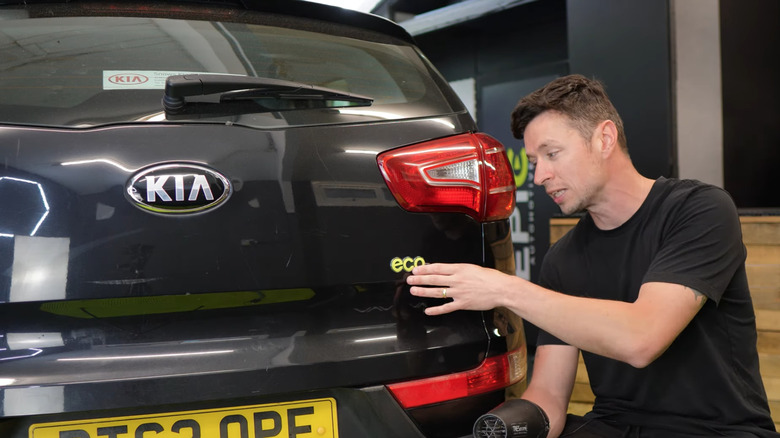Man sticking back his car badge after polishing