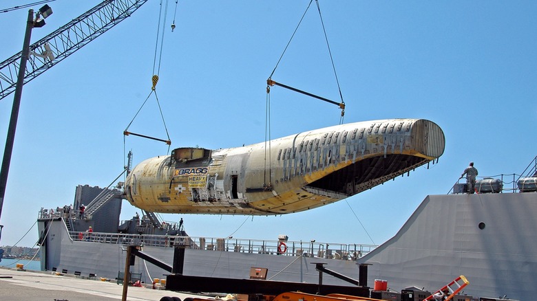 A Logistic Support Vessels using a crane to lower a C-17 fuselage into its cargo hold