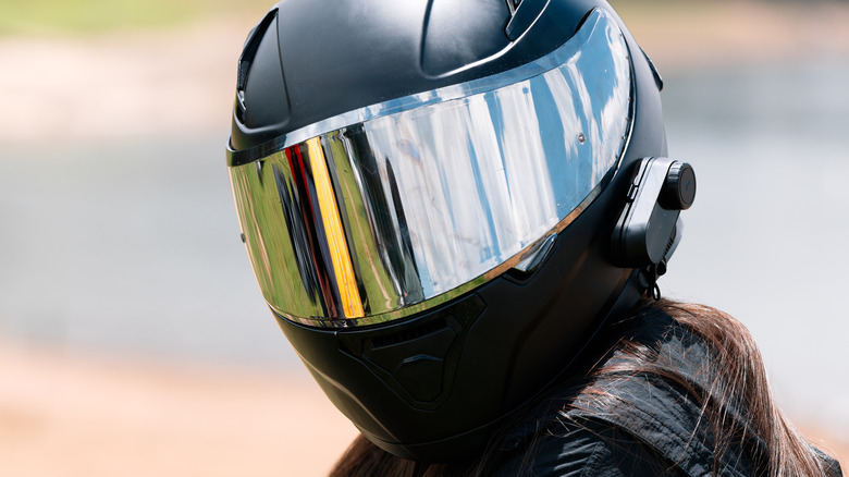 A person wearing a reflective motorcycle helmet.