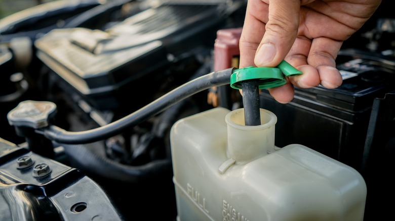 Person checking the coolant levels in the coolant tank in the engine