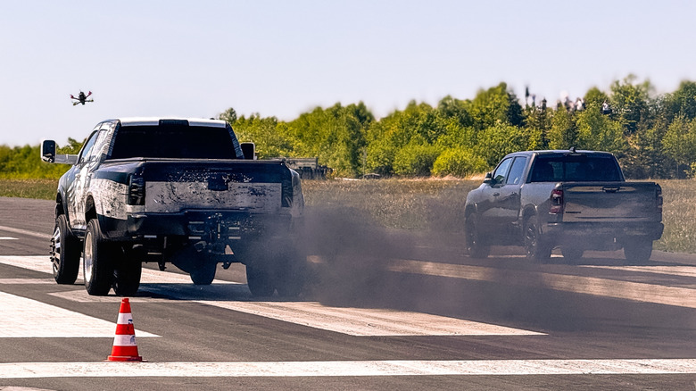 Ram trucks drag racing with black smoke emitting from exhaust pipes