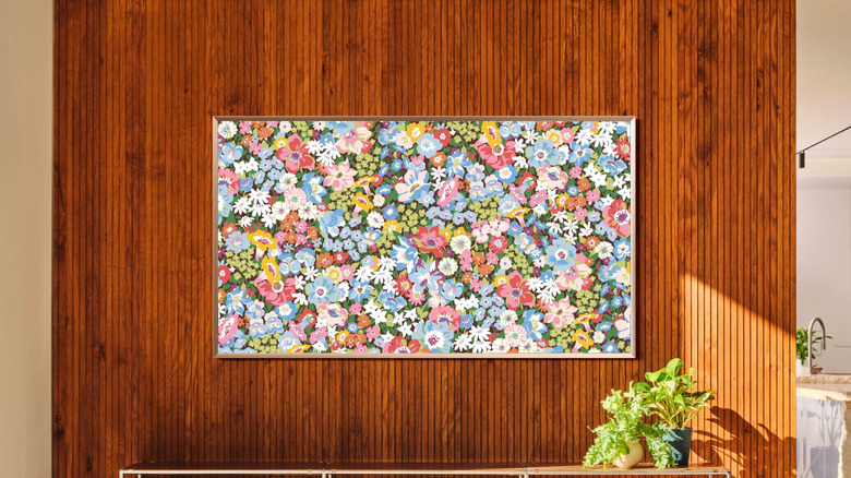 A framed flatscreen Samsung smart TV hanging in a cluttered dining room.