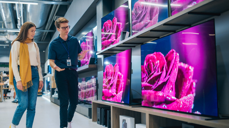 Young female buyer inquiring about smart TVs with the sales rep