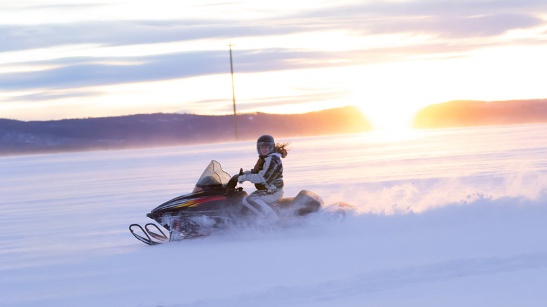 girl riding snowmobile in open
