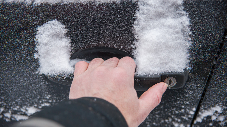 Attempting to open a frozen car door by hand.