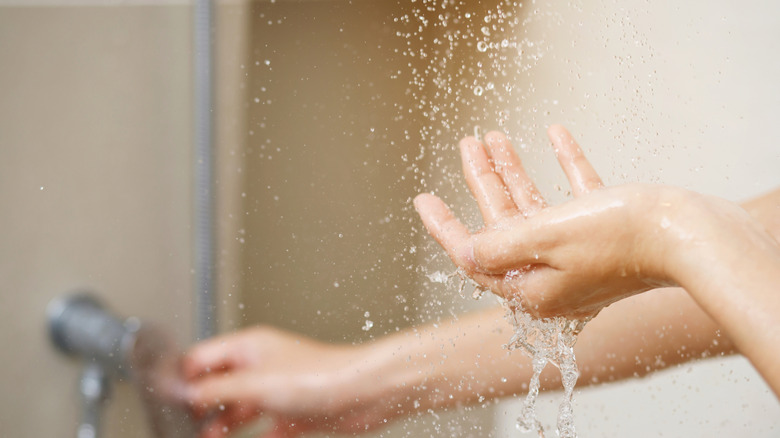 A person uses hand to measure the water temperature from a water heater