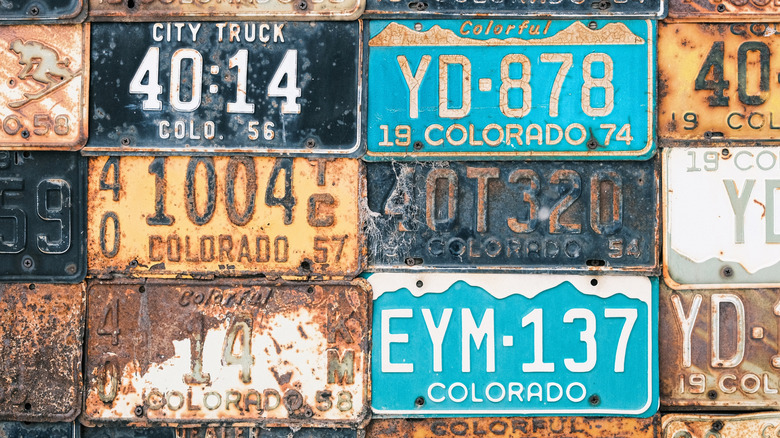 Old rusted license plates on a wall.