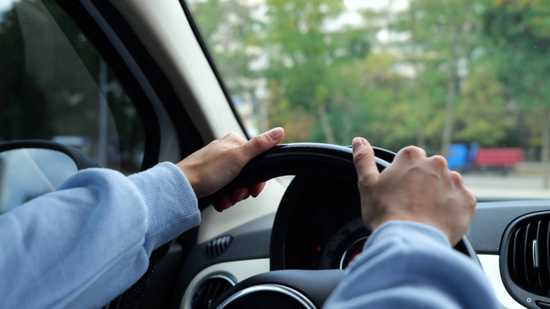 Close-up view of a driver's hands on a steering wheel.