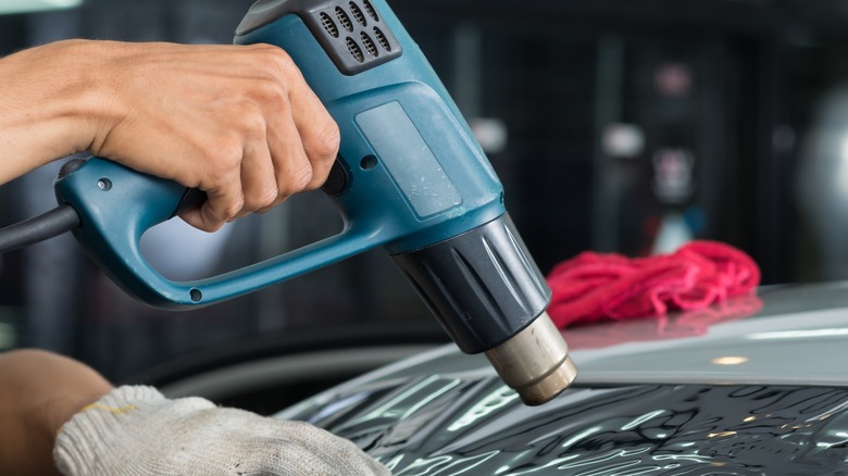 Person applying heat gun on car's surface