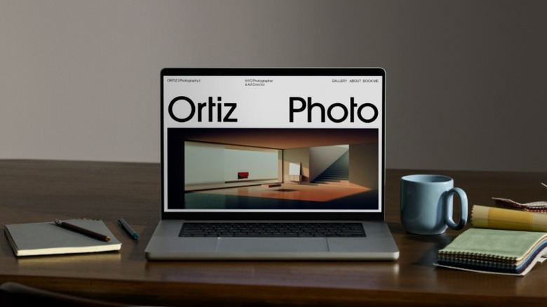 Ortiz Photo website on laptop on desk with blue mug and notepads