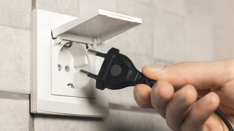 A person unplugging a power cord