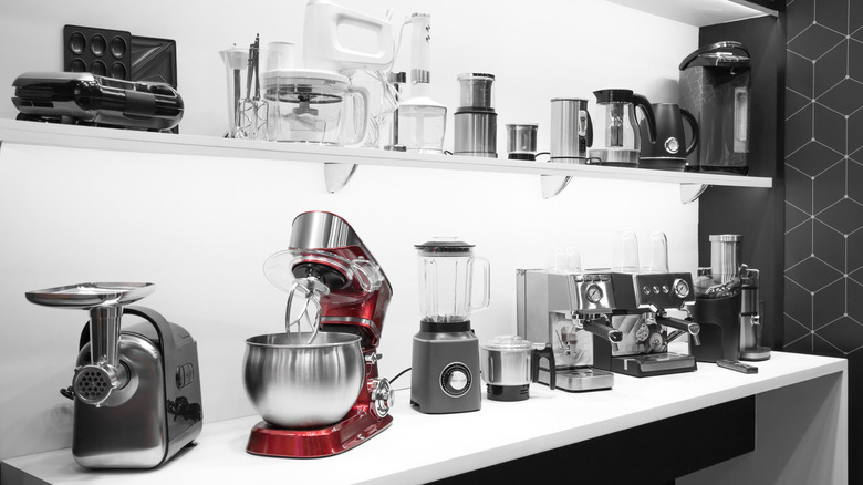 lots of small kitchen appliances on a counter and a shelf