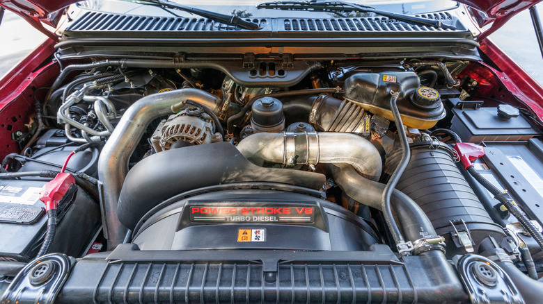 An engine bay of a red Ford truck showcasing a Power Stroke V8 turbodiesel engine