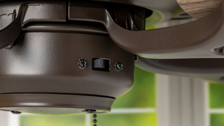 a closeup image of a ceiling fan showing the direction switch