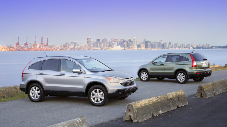 Two third generation Honda CR-Vs (silver and green) parked near a waterfront.