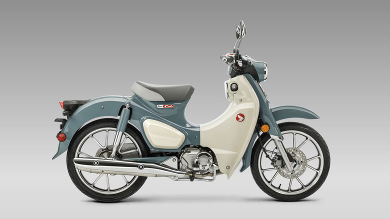 A blue and cream colored Honda Super Cub 125 version against a studio background.