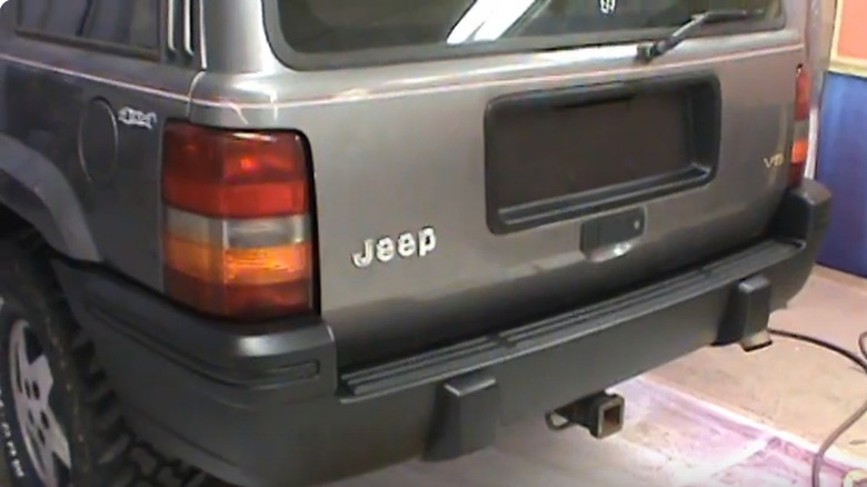 Rear view of a gray Jeep SUV, showing a freshly painted rear bumper.