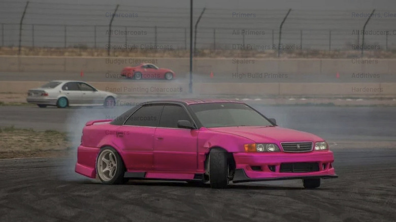 A bright pink drift car slides sideways on a racetrack.
