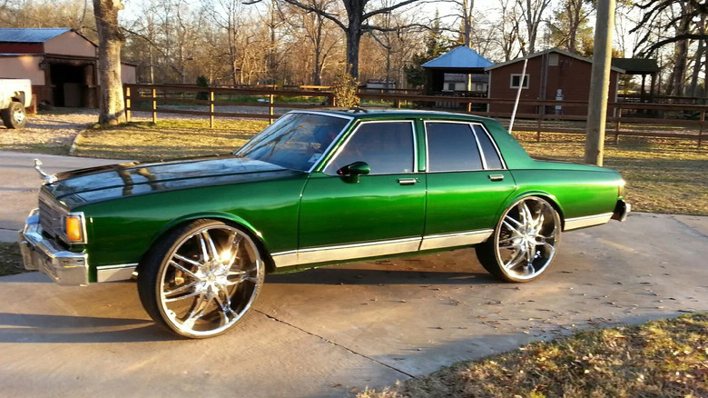 A lavender Mazda MX-5 Miata parked outdoors with its headlights partially raised.