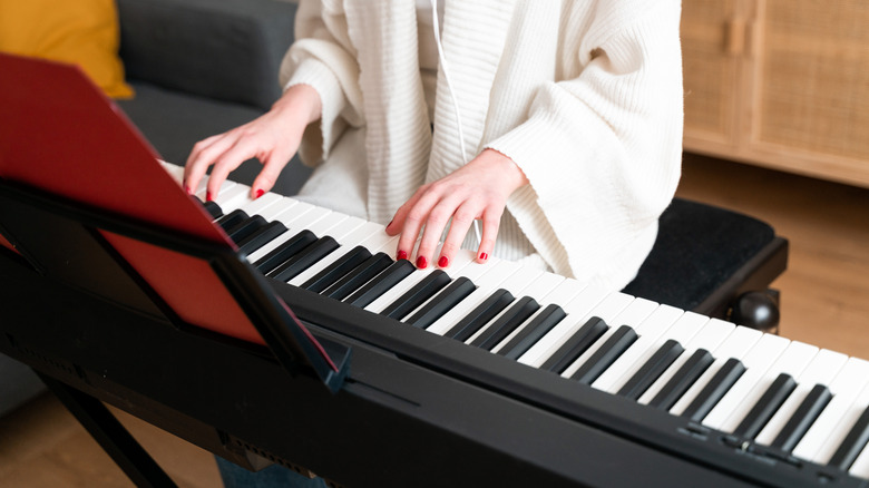 A musician sitting to play piano on an electric piano keyboard.