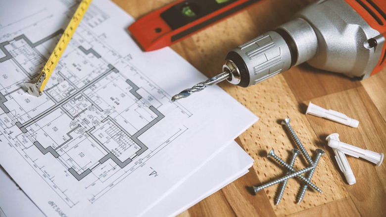 A Bauer drill next to blueprints and screws