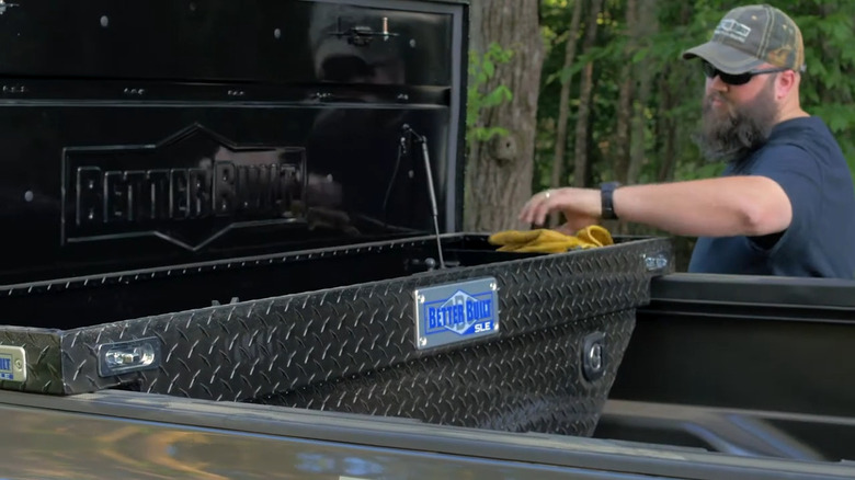 Person dropping gloves into a truck bed toolbox