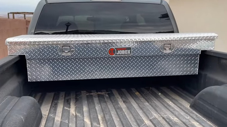 Bed of pickup with silver toolbox mounted near cab
