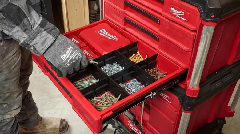 A person wearing gloves takes some screws from a Packout 4-Drawer Tool Box