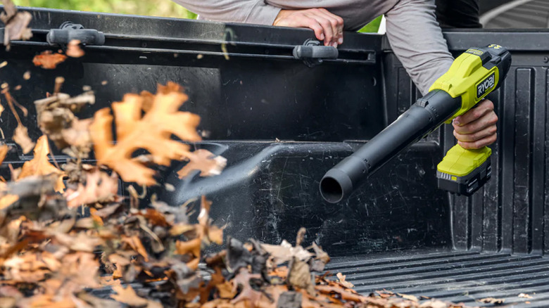 A man using a handheld leaf blower to blow out his truck
