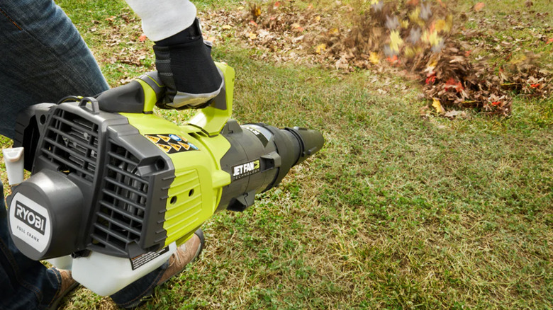 A man using a gas-powered Ryobi leaf blower