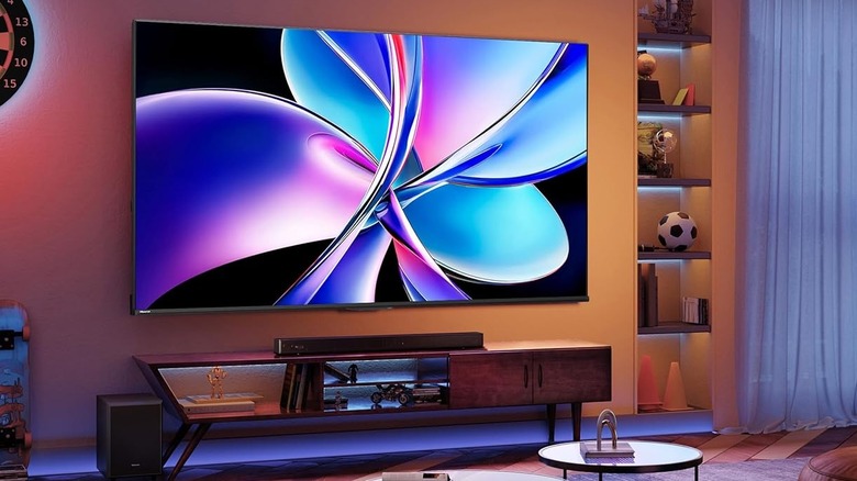 A Hisense TV with Dolby Vision on a wall over a TV stand and sound bar.