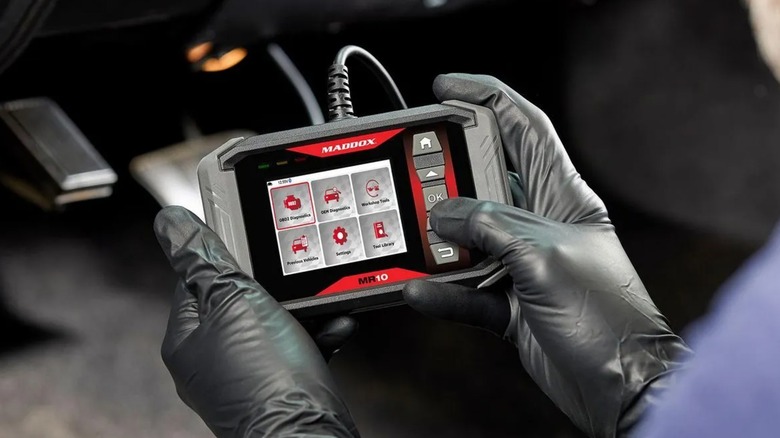 Person using the Maddox MR10 OBDII Code Reader in a car