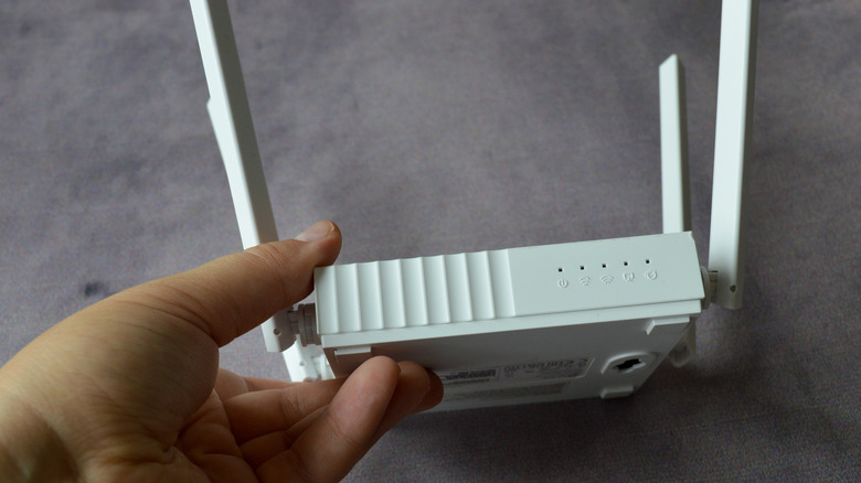 Wi-Fi router with four antennas held in hand.