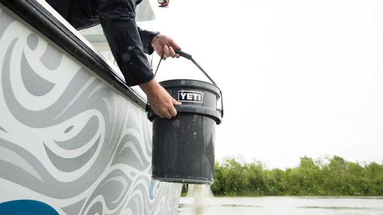 A person holding a Yeti 5-gallon bucket out of a boat.