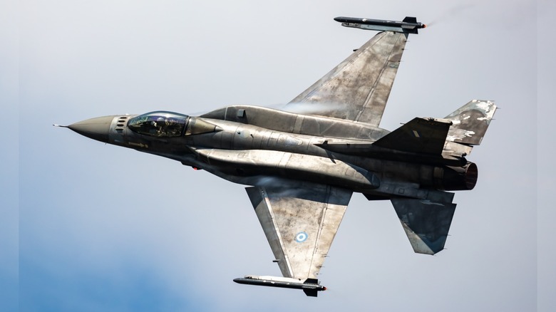 A view of the top of an F-16 Fighting Falcon as it banks left with an overcast background.