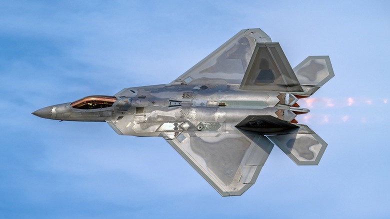 A maneuvering F-22 Raptor seen with flames coming out of its afterburners