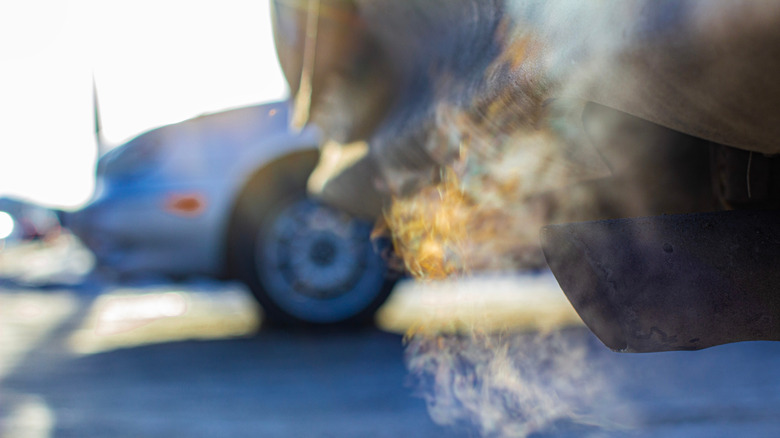 Close-up of a car idling in place with sun and a different car in the background.
