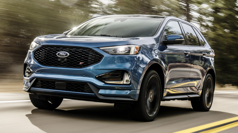 Blue 2019 Ford Edge ST driving down a road with trees in the background