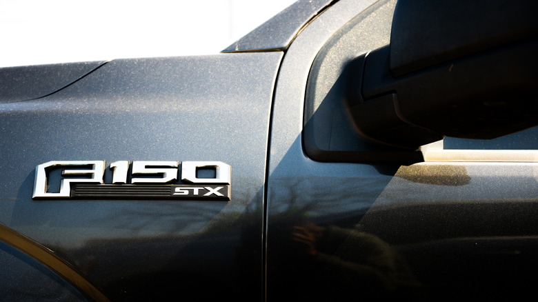 A close-up of a F-150 STX badge on a black Ford truck