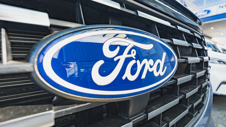 A close-up shot at an angle of the Ford blue oval emblem on the front of a car