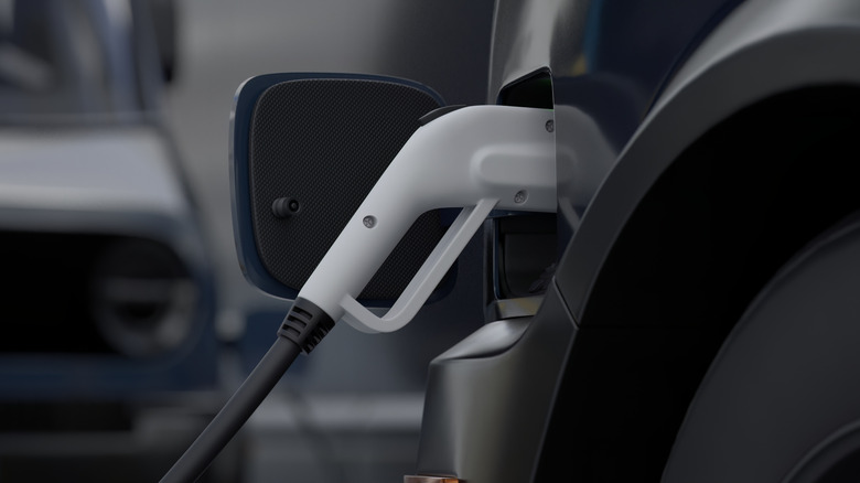A white charger plugged into black EV