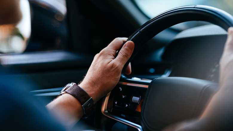 man holding leather steering wheel