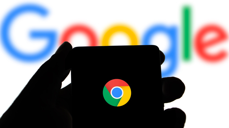 Silhouette of a person holding phone with Chrome logo in front of Google logo