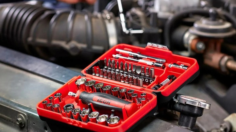 A person using a socket wrench beside an opened Icon socket set.