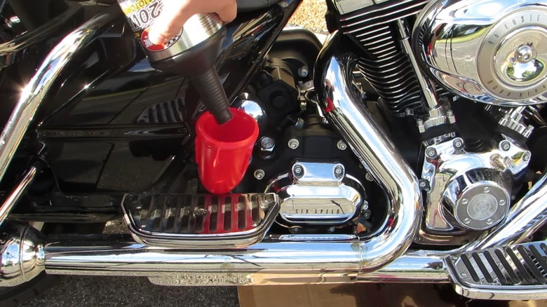 A person changing the oil on a Harley-Davidson motorcycle