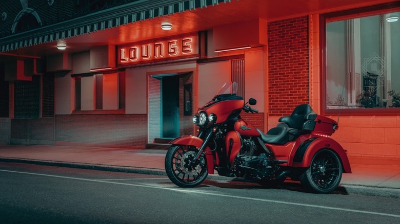 An orange Harley-Davidson Tri Glide Ultra parked in front of a diner at night.