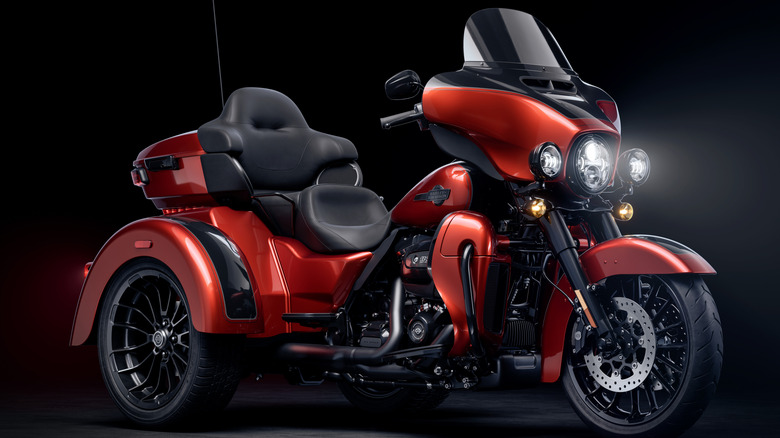 An orange Harley-Davidson Tri Glide Ultra against a black background.
